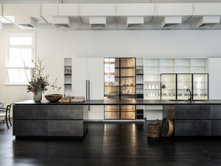 open-plan kitchen with a dark stone island and white shelving