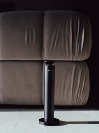 kirri beacon diffuser standing beside a velvet sofa