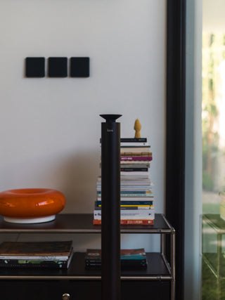black kirri beacon diffuser in front of a styled shelf of books and an orange ceramic