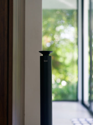 close up of a black kirri beacon diffuser in front of a window and garden