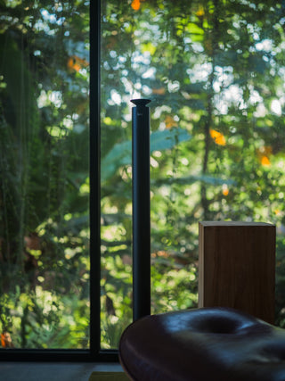 tall black kirri diffuser beside a floor-to-ceiling window looking out to greenery