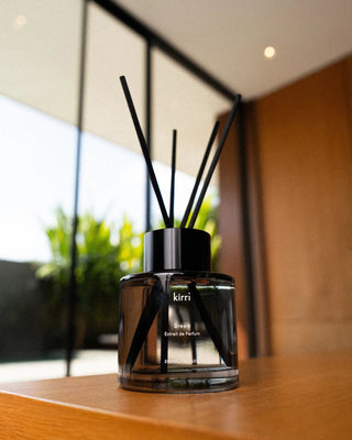 kirri reed diffuser with black reeds on a timber bench by the window