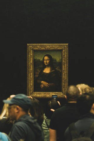 the mona lisa on display at the louvre, with visitors in the foreground
